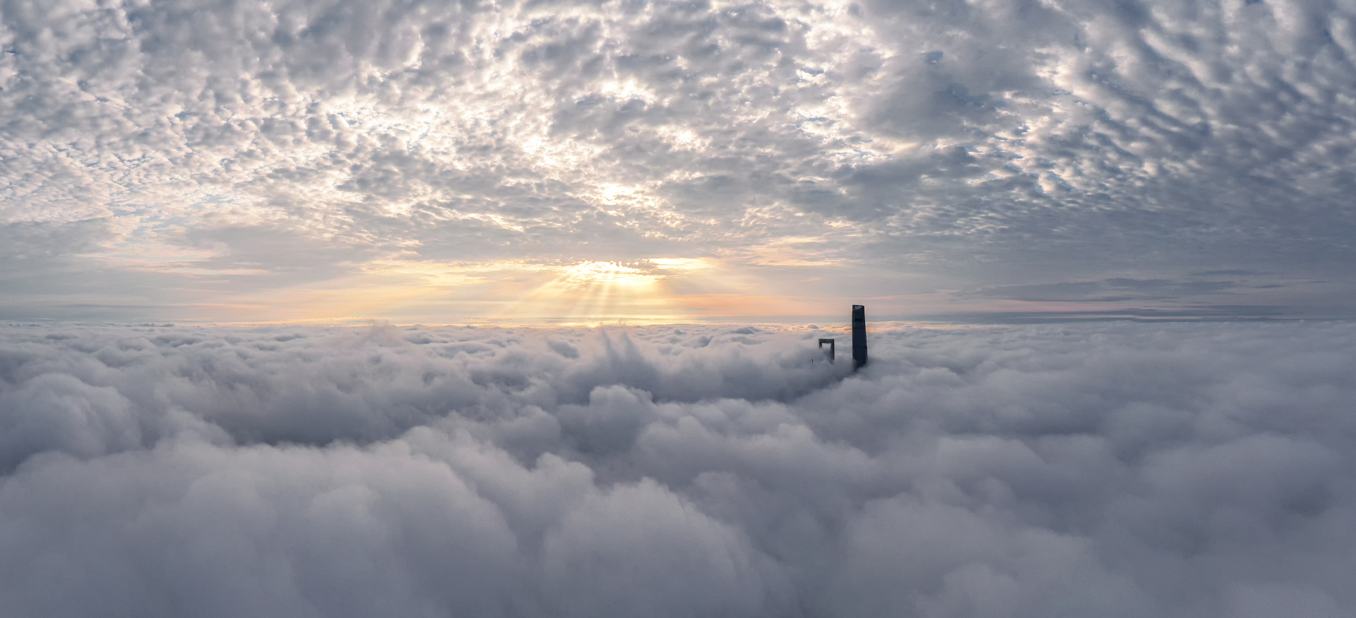 A stone tower protruding between levels of clouds